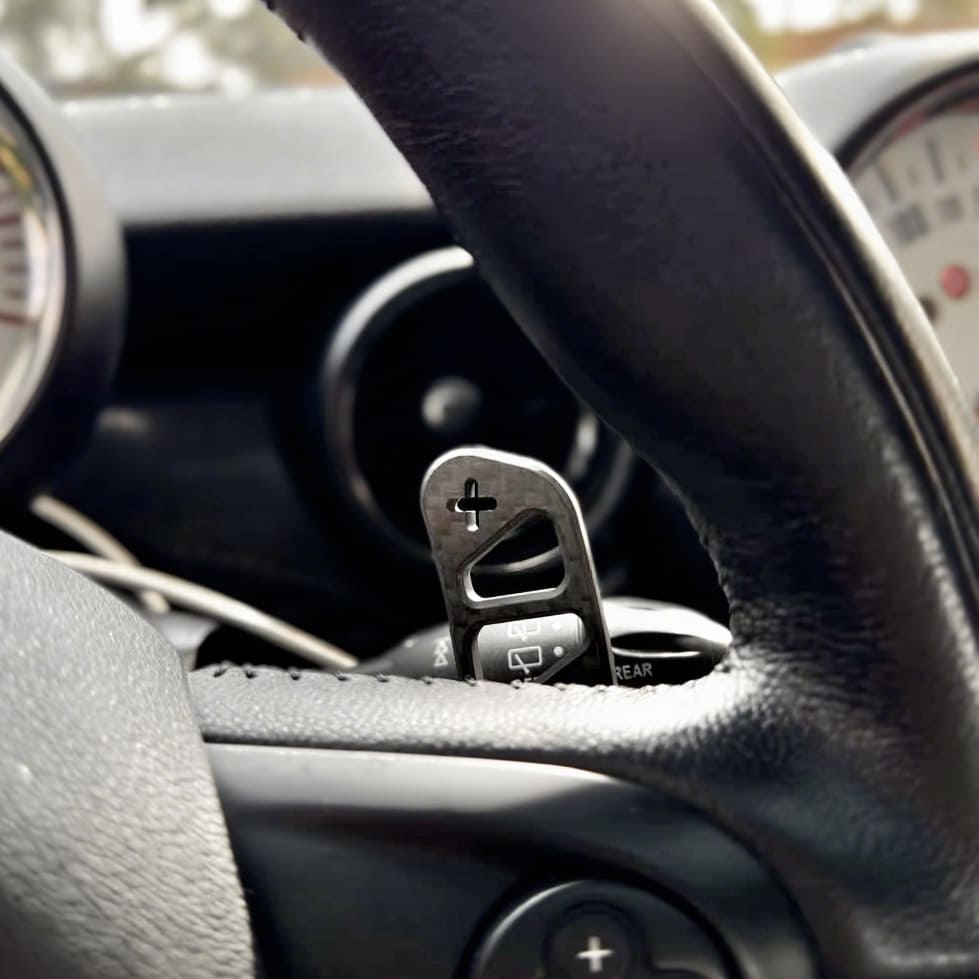 Detailed view of custom mini cooper part magnetic carbon fiber paddle shifter installed on a MINI Cooper R56 steering wheel