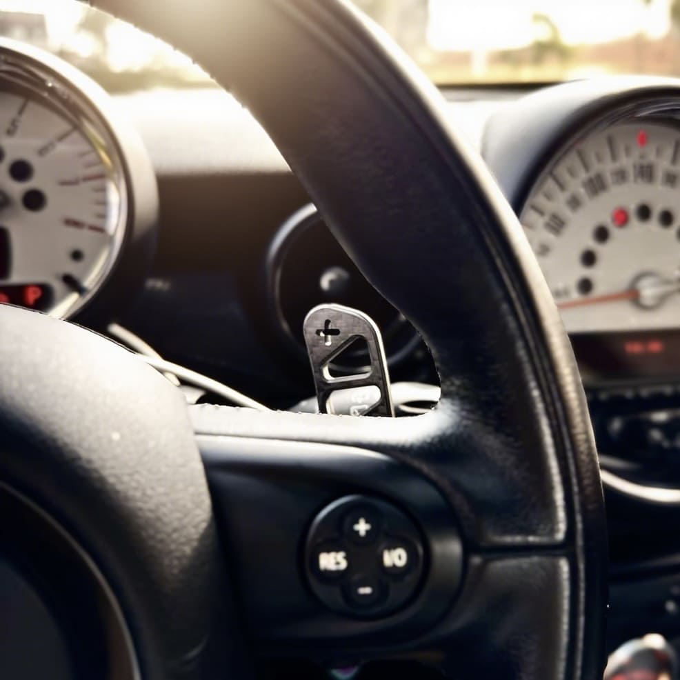 Installed aftermarket mini cooper magnetic carbon fiber paddle shifter on the steering wheel of a MINI Cooper R56, showing sleek OEM upgrade
