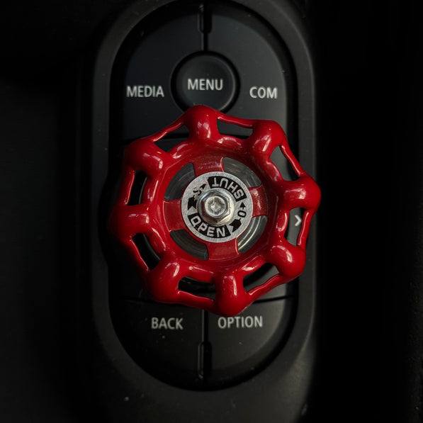 Overhead shot of the red aluminum iDrive controller decoration in a MINI Cooper F56, highlighting its bold contrast against the center console.