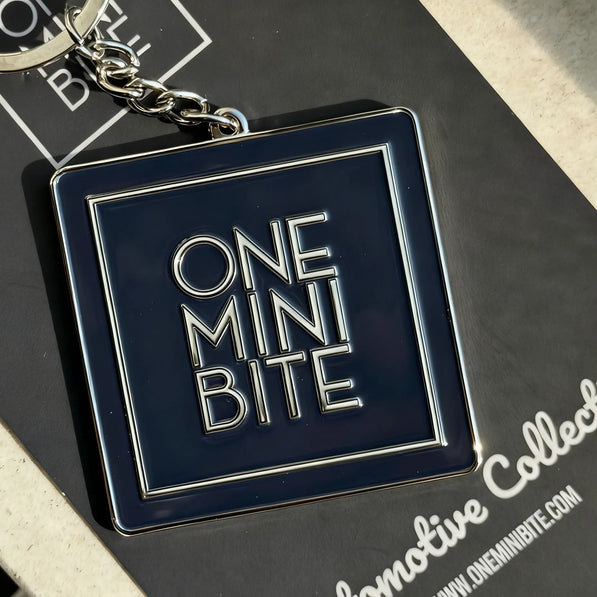 ONEMINIBITE square logo keychain shown in a lifestyle setting attached to keys