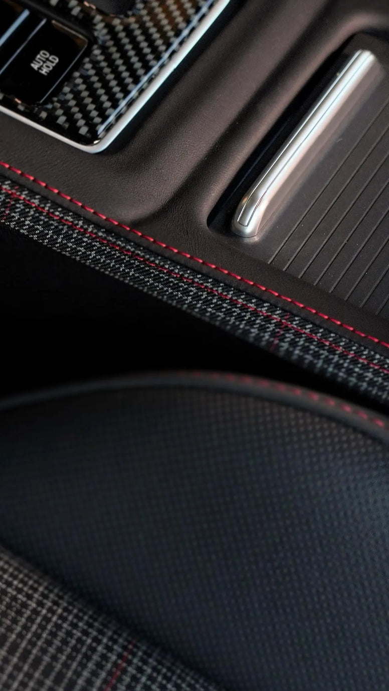 Close-up of VW Golf 8 R center console upgraded with OneMiniBite custom Alcantara and carbon fiber interior trim.