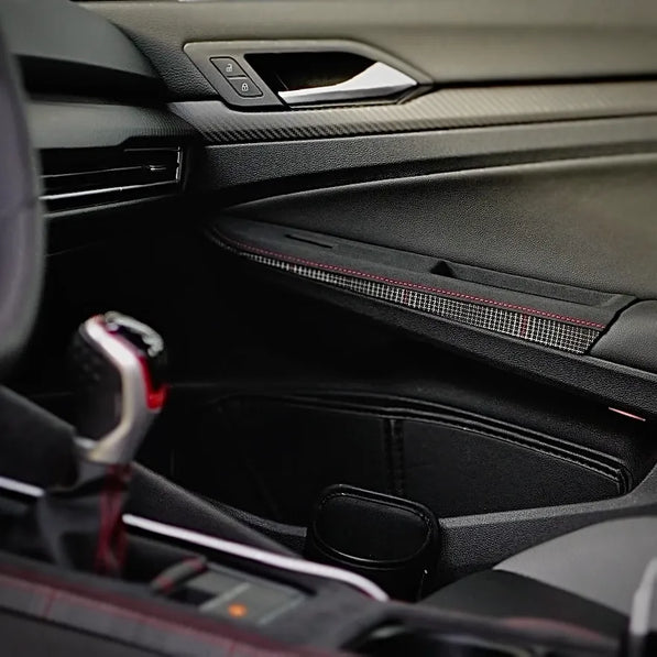 Overlay-style door control panel cover installed on a VW Golf Mk8 GTI, showing OEM-aligned fitment, extended switch cutouts, and a plaid semi-rough leather finish designed for daily use.
